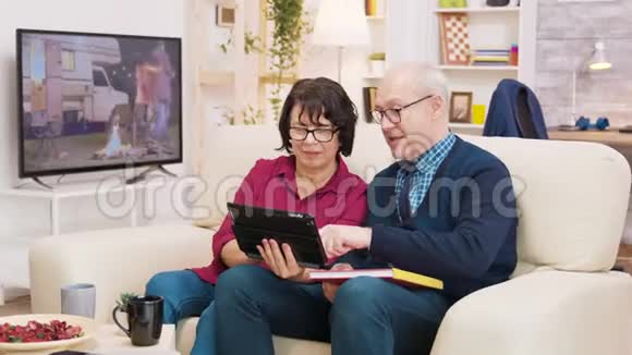 一对老夫妇坐在沙发上看平板电脑视频视频的预览图