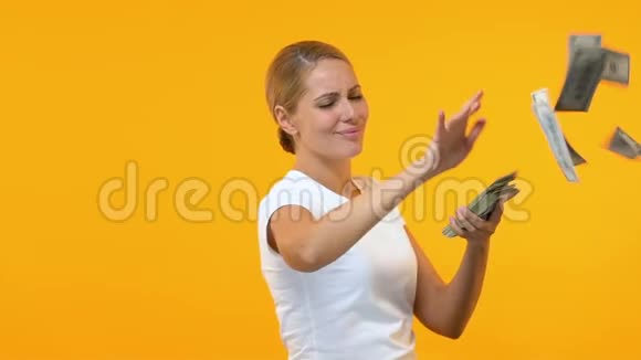 非常快乐的女人在橙色背景下扔美元彩票中奖者视频的预览图