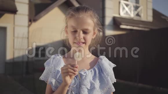 一个漂亮可爱的小女孩吹着蒲公英微笑着看着镜头的肖像孩子花时间视频的预览图