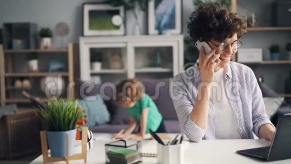 女孩在家玩手机时用手提电脑工作视频的预览图