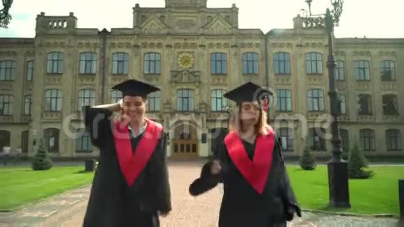 两个坐在壁炉里的女孩走向大学大楼年轻人庆祝他们的毕业典礼毕业新生活视频的预览图