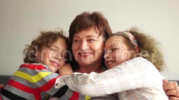 微笑的祖母和孙子拥抱的肖像祖母和两个卷曲的孙子一个男孩和一个女孩视频的预览图