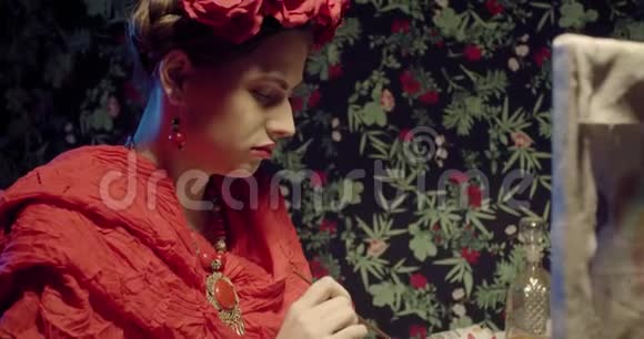 年轻的弗里达卡洛FridaKahlo穿着红色披肩头发上戴着花正在画画4K视频的预览图