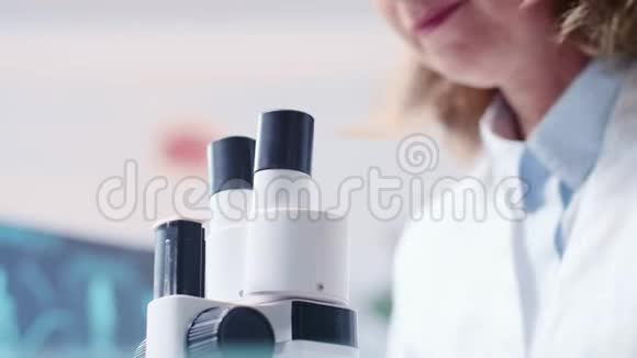 成熟女性研究者通过显微镜观察低角度手持镜头视频的预览图