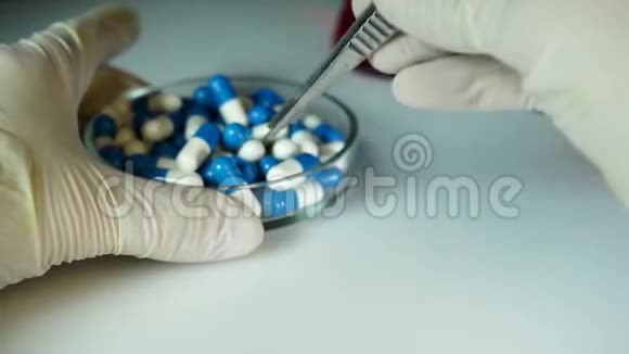 医生用镊子拿了一个新药的胶囊然后转移它概念药物测试药物质量视频的预览图