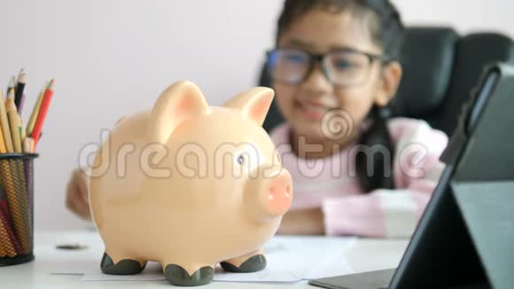 小亚洲女孩把硬币放进储蓄罐里在未来的教育中带着快乐的微笑为节省金钱而财富视频的预览图