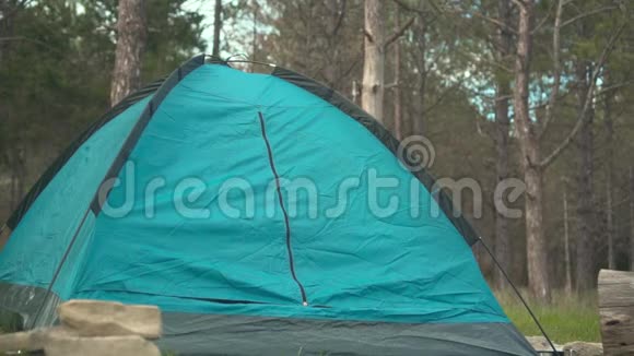 一个年轻人从森林里的内部打开蓝色帐篷的锁向外看享受这一刻视频的预览图