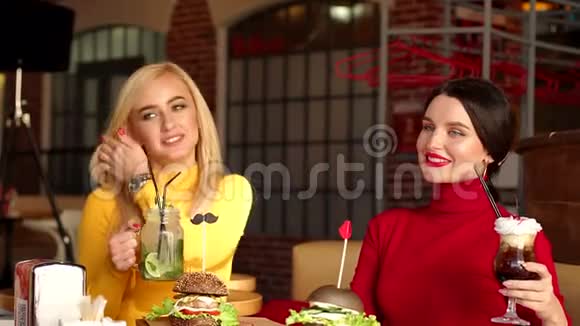 两个年轻的女朋友在咖啡馆里休息她们喝着明亮的鸡尾酒视频的预览图