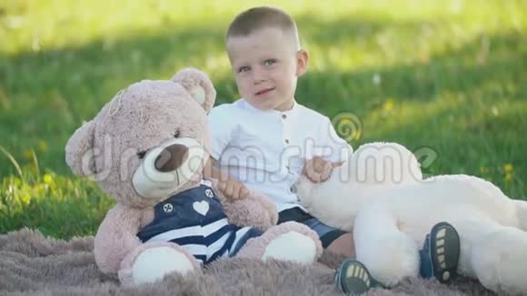 有软玩具的男孩坐在毯子上视频的预览图