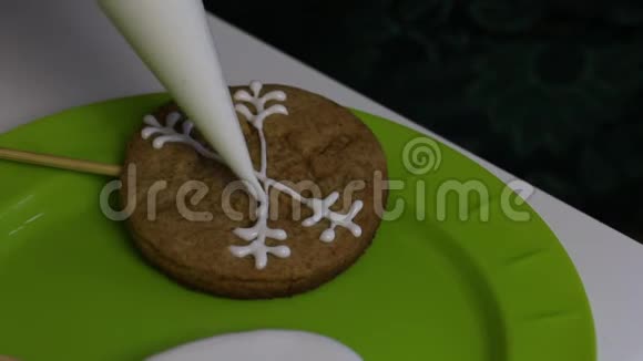 一个女人正在把白糖糖霜涂在心形姜饼饼干上餐盘附近有带糖霜的饼干视频的预览图