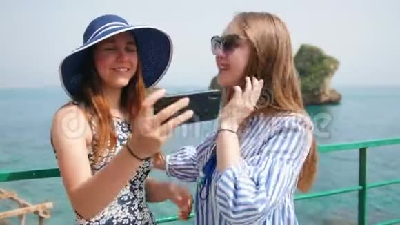 两位年轻女子正在大海的背景下拍摄视频的预览图