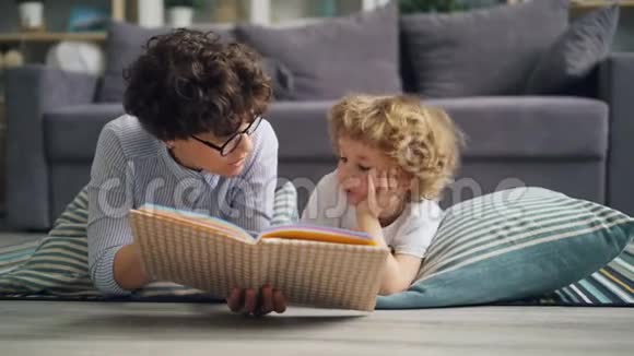 小女孩妈妈在家给好奇的男孩读书在地板上讨论故事视频的预览图