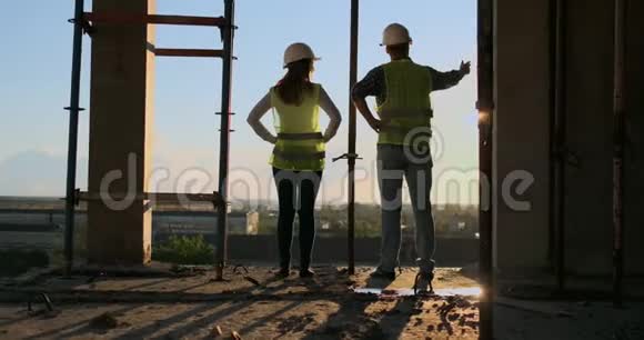 白色头盔和绿色背心的白种人建筑工人的背面和侧面看图站在未完成的视频的预览图
