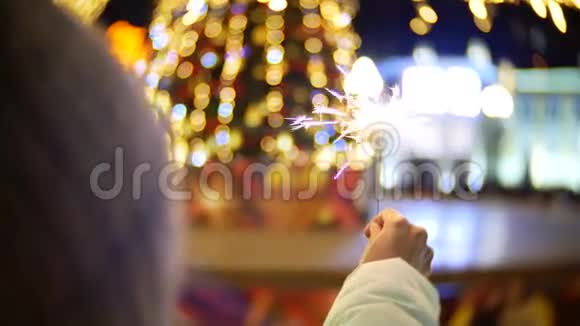 女人的手在圣诞树前拿着火花视频的预览图