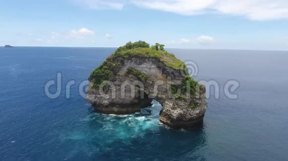 桡动无人机拍摄的一块巨大的岩石在海洋中有一个拱门印度尼西亚4k视频的预览图