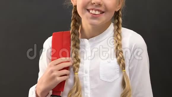 微笑的小女孩背着背包站在黑板上准备上学视频的预览图