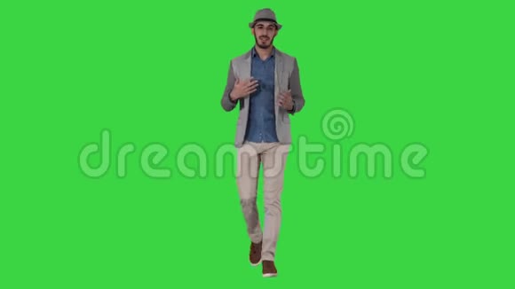 时尚时尚积极开朗的男士穿着休闲衬衫戴着遮阳帽在绿色屏幕上与摄像机交谈视频的预览图