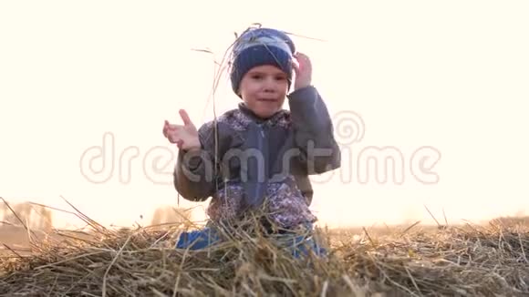 一个孩子坐在干草堆上他又玩又笑乡村日落视频的预览图