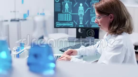 在笔记本电脑上打字的科学家女士手持照片视频的预览图