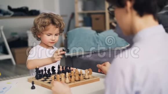 快乐的男孩玩棋子而妈妈教他玩游戏视频的预览图