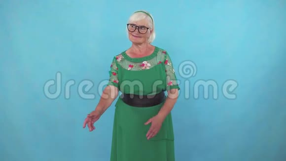 一位漂亮的老妇人站在蓝色的背景上视频的预览图