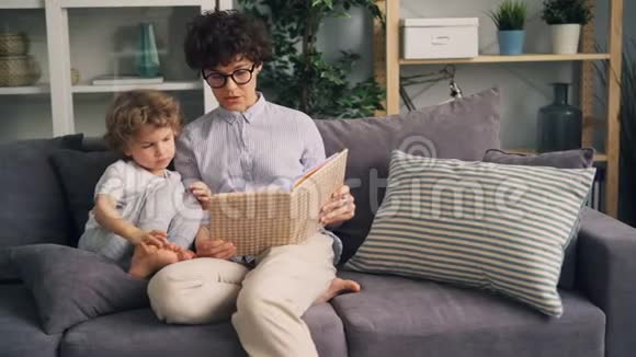 快乐的女人给小男孩读有趣的故事笑着在家玩视频的预览图