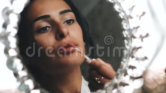 女孩看着镜子画着她的嘴唇漂亮的特写女性美丽视频的预览图