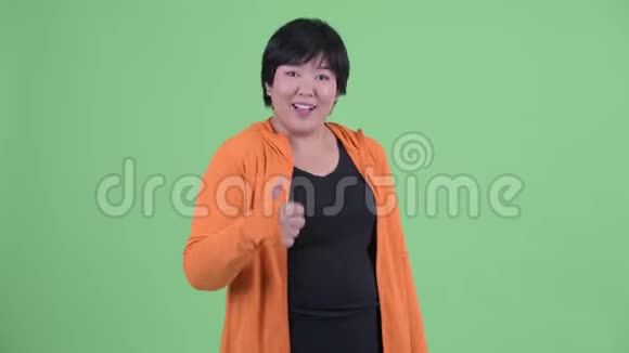 快乐年轻体重超重的亚洲女人竖起大拇指准备去健身房视频的预览图
