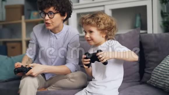 兴奋的孩子和妈妈一起玩电子游戏微笑着享受家庭活动视频的预览图
