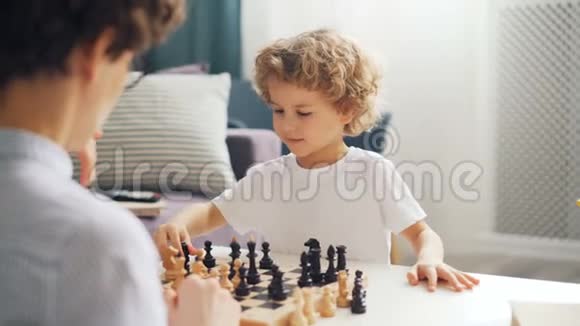 情绪激动的小孩子和妈妈下棋在船上移动棋子微笑着视频的预览图