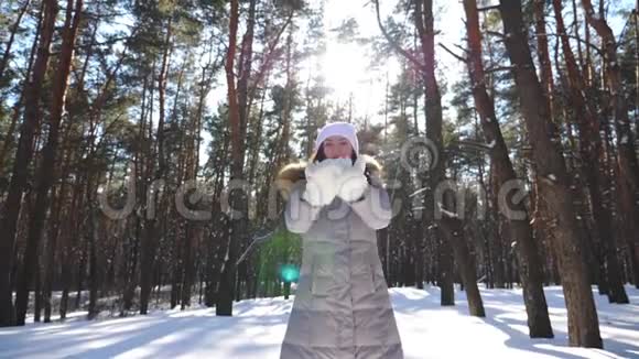 年轻快乐的女人穿着冬天的衣服扔一把雪享受飘落的雪花可爱的女孩在玩视频的预览图