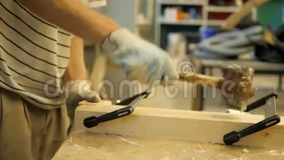 木工车间的一位工匠用橡皮锤敲着用夹子固定的木板视频的预览图