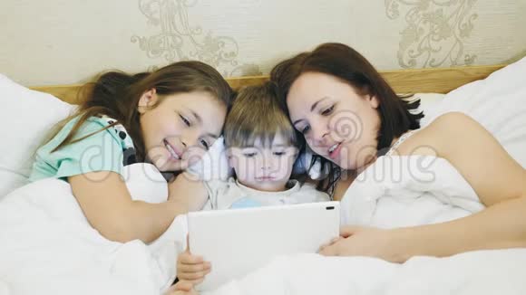 一家人在床上看着平板电脑上的东西视频的预览图