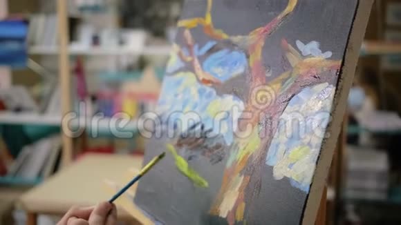 艺术家在艺术学校的黑帆布上涂黄水粉特写视频的预览图