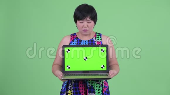 年轻肥胖的亚洲女性展示笔记本电脑视频的预览图