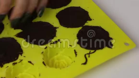 一个女人从硅胶里取出巧克力釉糖把它们放到盘子里视频的预览图