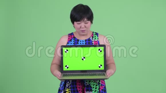 快乐的年轻超重的亚洲女人带着笔记本电脑看上去很惊讶视频的预览图