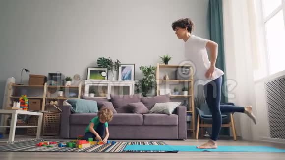 小男孩玩积木而妈妈漂亮女孩做瑜伽平衡视频的预览图
