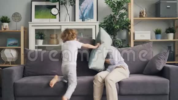 年轻女子和儿子玩捉迷藏然后枕头打架笑了起来视频的预览图