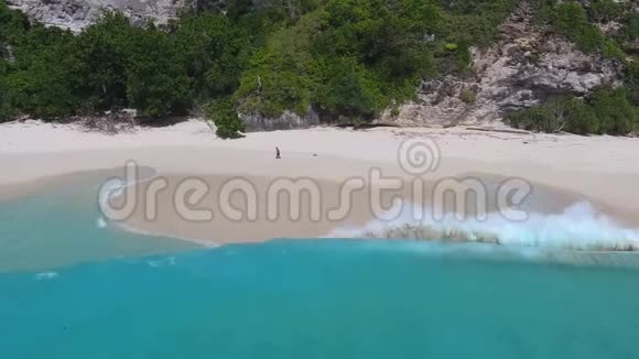 一个男人正在热带海滩上的沙滩上写作蓝色的水阳光明媚的一天4K视频的预览图