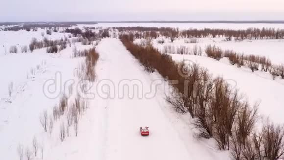 一辆车正沿着一条冬天下雪的乡村道路行驶从无人驾驶飞机上俯瞰视频的预览图