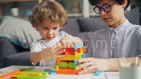年轻女子和她的小孩在家里玩木积木视频的预览图