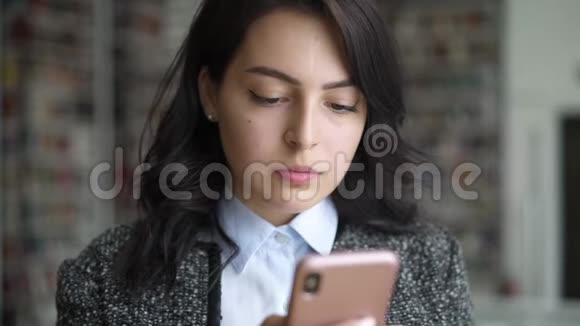在书架背景上打电话发短信的亚洲年轻女子视频的预览图