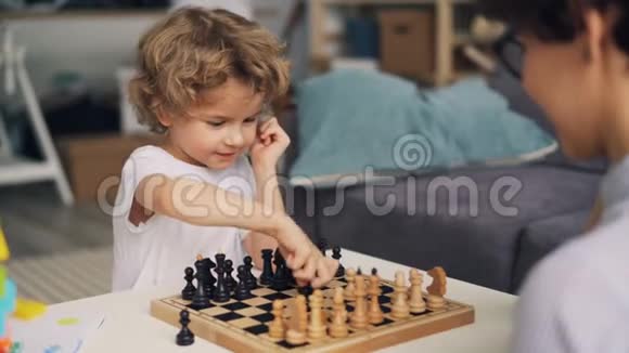 聪明的男孩下棋妈妈移动棋子表达积极的情感视频的预览图