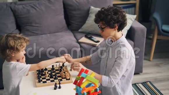 可爱的孩子学会下棋和快乐的年轻妈妈一起玩视频的预览图