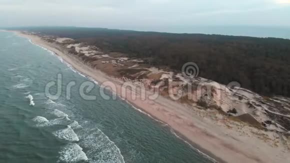 日落后蓝色小时的波罗的海海岸鸟瞰图暮光的海岸线带着滚滚的波浪空旷的海滩视频的预览图