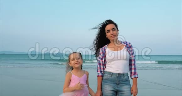 母亲和女儿正沿着海岸散步幸福的家庭在海边散步视频的预览图