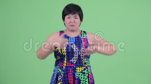 年轻肥胖的亚洲女性在拇指向上和拇指向下之间做出选择视频的预览图