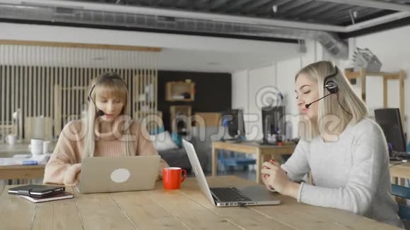 两位女士戴着耳机看着笔记本电脑女客户支持经理翘首以待视频的预览图