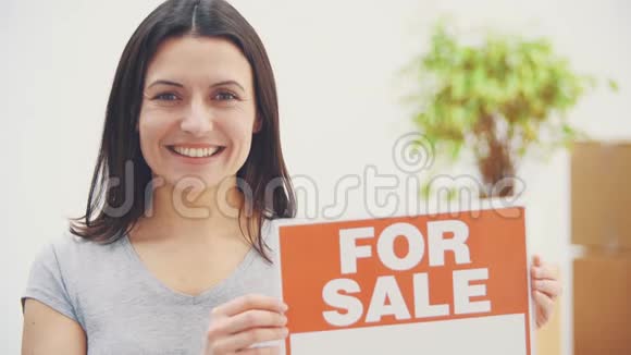 年轻漂亮的女人拿着一个盘子上面写着出售的文字提供出售的房子然后搬出视频的预览图